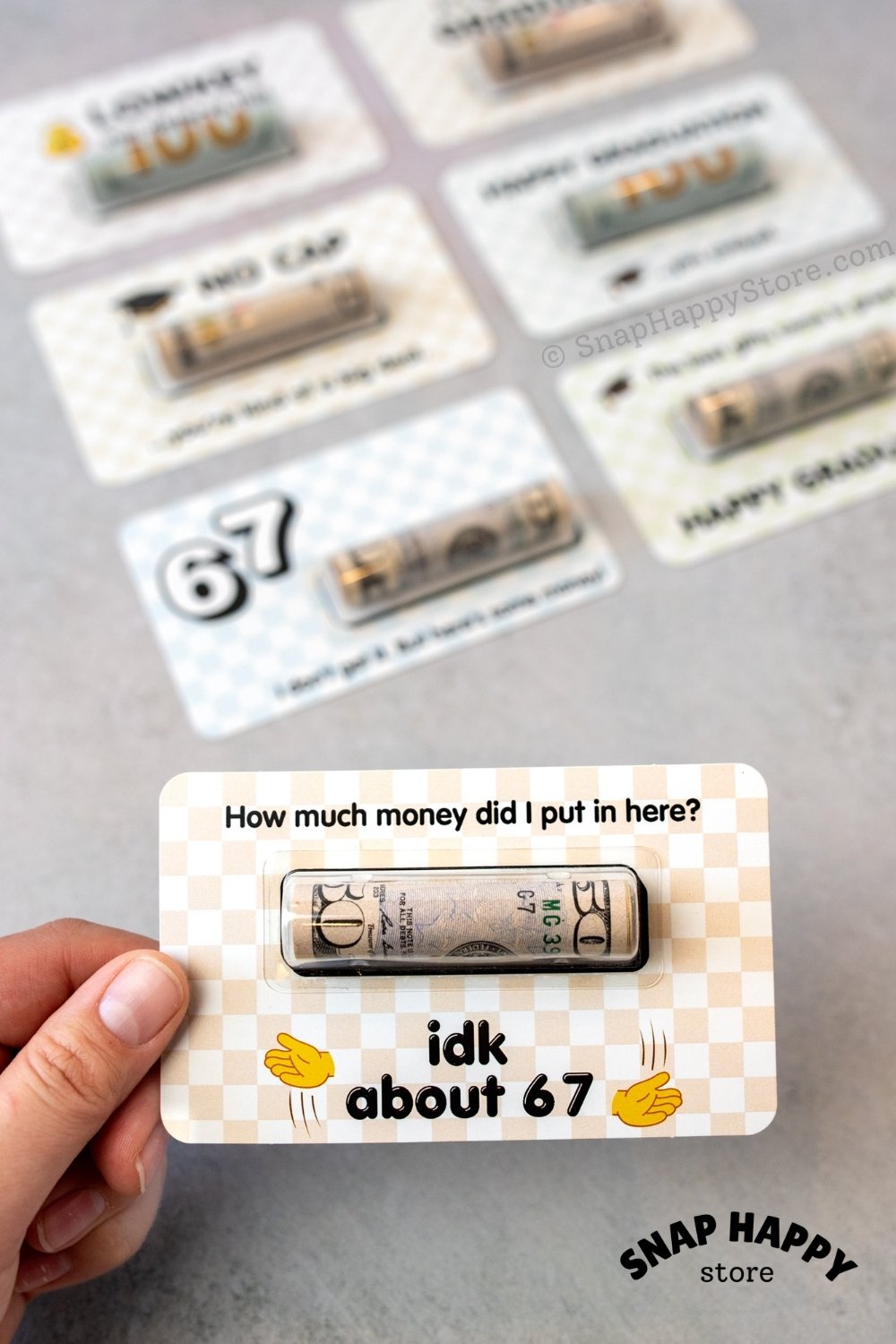 Card with a humorous 67 question a money held by a hand on a gray surface.